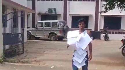 திருப்புவனம்: வட்டாட்சியர் அலுவலகத்தில் பட்டா பெற முடியாத ஆத்திரத்தில் இது வரை அளித்த மனுக்களை மாலையாக போட்டுக்கொண்டு வாலிபர் போராட்டம்
