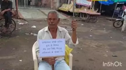 गुना नगर: जयस्तंभ चौराहे पर छाता लगाकर धरने पर बैठे बुजुर्ग व्यापारी, पुरानी गल्ला मंडी में अतिक्रमण कार्यवाही में पक्षपात का आरोप