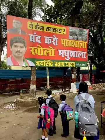 स्कूलविलय को लेकर हुई सियासी गर्मीतेज सपा कार्यालय के बाहर पोस्टर मे लिखा ये कैसा रामराज्य बंद करो पाठशाला खोलो मुधशाला