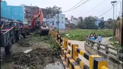 बिहार: शहरी इलाके से पानी निकासी के लिए नगर निगम की टीम आशा नगर पूल के पास नाडी से जल कुंभी निकाल रही है