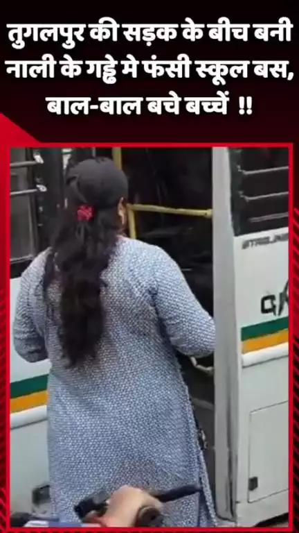 दादरी: तुगलपुर में सड़क के बीच बनी नाली के गड्ढे में फंसी स्कूल बस, बाल-बाल बचे बच्चे